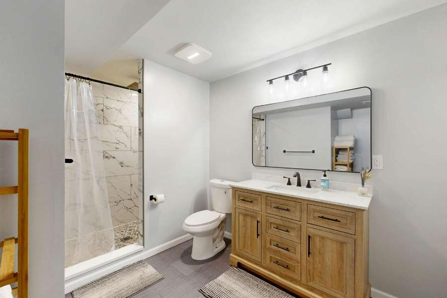 Petite salle de bain moderne avec meuble vasque en bois, grand miroir et douche en marbre pour décorer une petite salle de bain