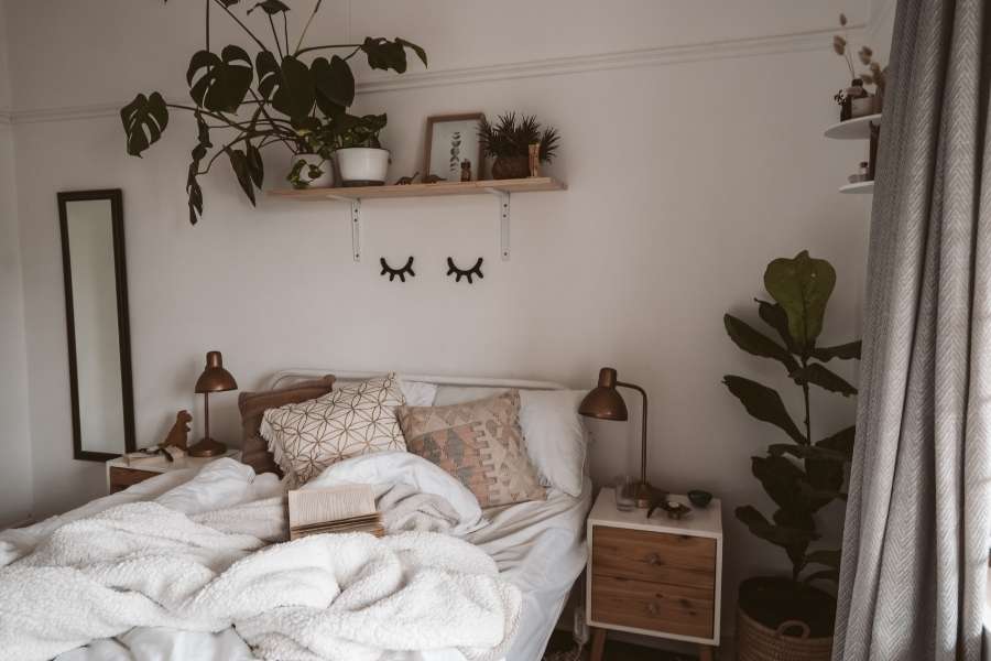Petite chambre aménagée avec style boho, étagère murale, plantes vertes et linge blanc douillet