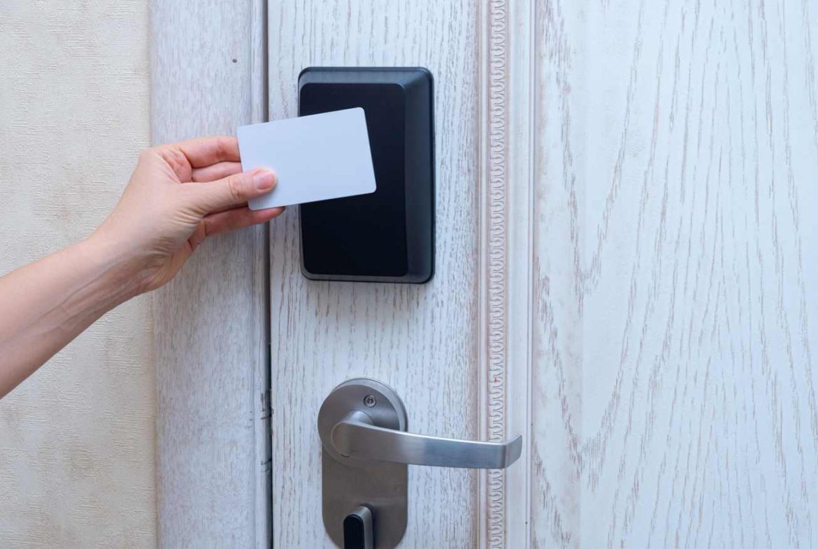 Une main approche une carte magnétique d'une serrure électronique installée sur une porte en bois pour refaire une cle securisee carte de propriete serrurier paris.