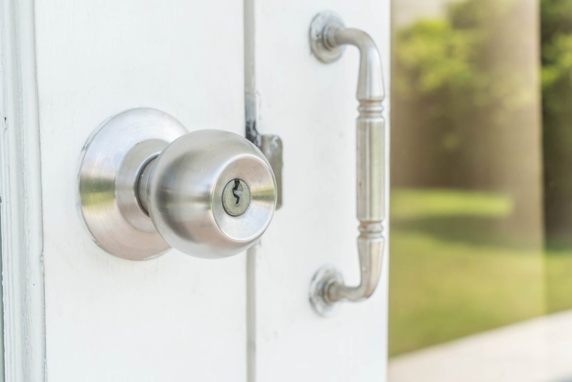 Gros plan sur la poignée et le cylindre d'une porte d'entrée blanche, montrant une installation de serrure multipoint pour menuiserie pvc.